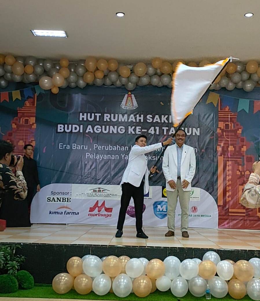 dr M Fachri M Nur Rahmatu mengibarkan pataka usai menerimanya dari dr Ida Bagus Yadnya Putra pada acara sertijab Dirut RS Budi Agung di salah satu hotel di Kota Palu, Minggu (22/1/2023). Foto: IST.