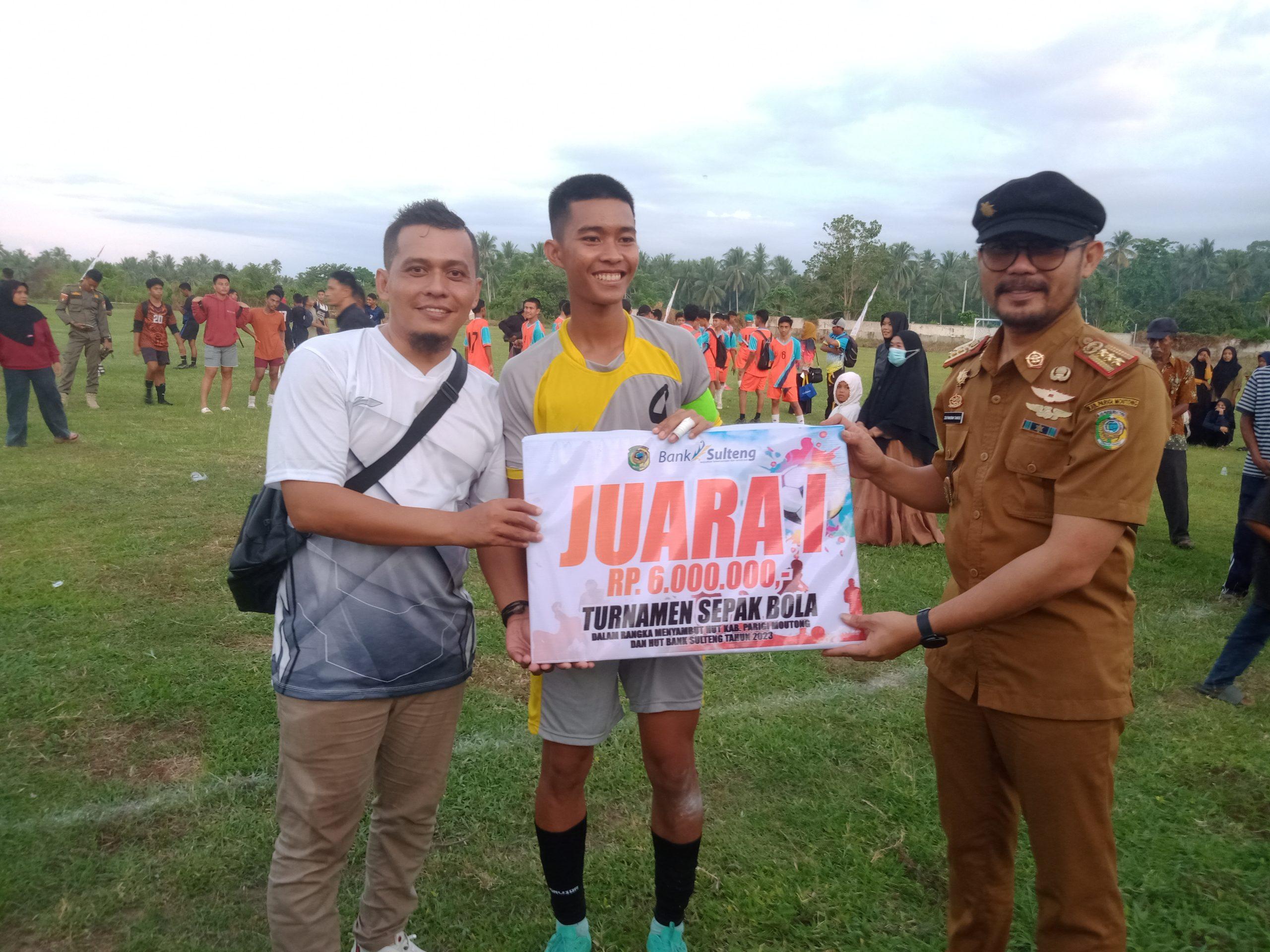 Sekda Parmout, Zulfinasran menyerahkan hadiah bonus kepada kapten kesebelasan U-17 Kecamatan Tinombo didampingi Camat Tinombo di stadion Jonokalora, Selasa (21/3/2023). FOTO: ASLAN LAEHO