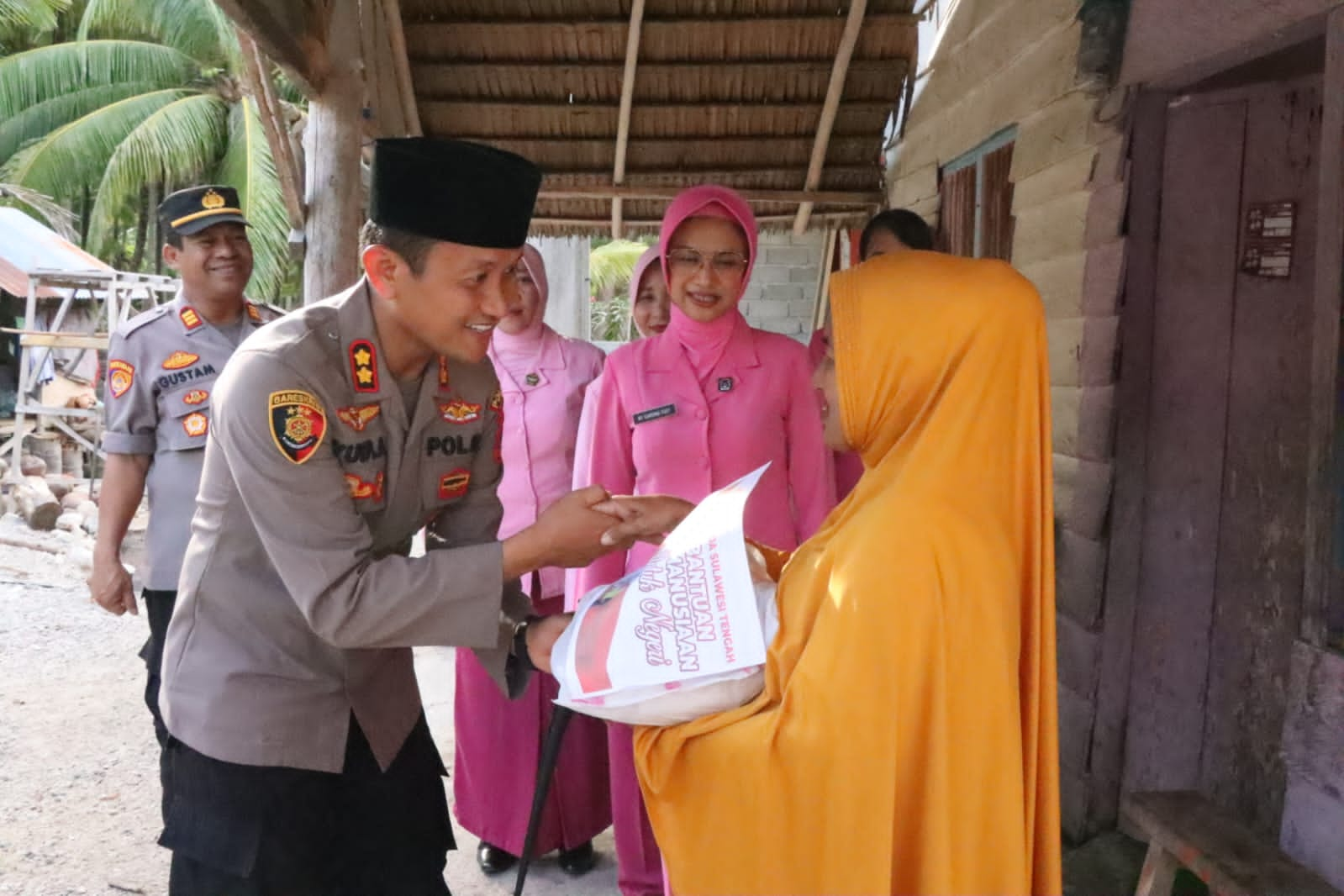 Kapolres Parmout, Yudy Arto Wiyono didampingi Ketua Bhayangkari Cabang Parmout, Gardina Yudy Arto menyerahkan sembako kepada salah satu warga di perumahan nelayan Dusun V Desa Pelawa Kecamatan Parigi Tengah, Sabtu (2/4/2023). FOTO: HUMAS POLRES PARMOUT.