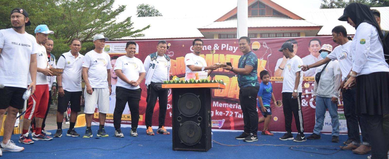 Ketua PBSI Sulteng, Gufran Ahmad menyerahkan potongan tumpeng kepada salah satu jajarannya pada peringatan HUT ke-72 PBSI di lapangan vatulemo, Ahad (14/5/2023). FOTO: IST