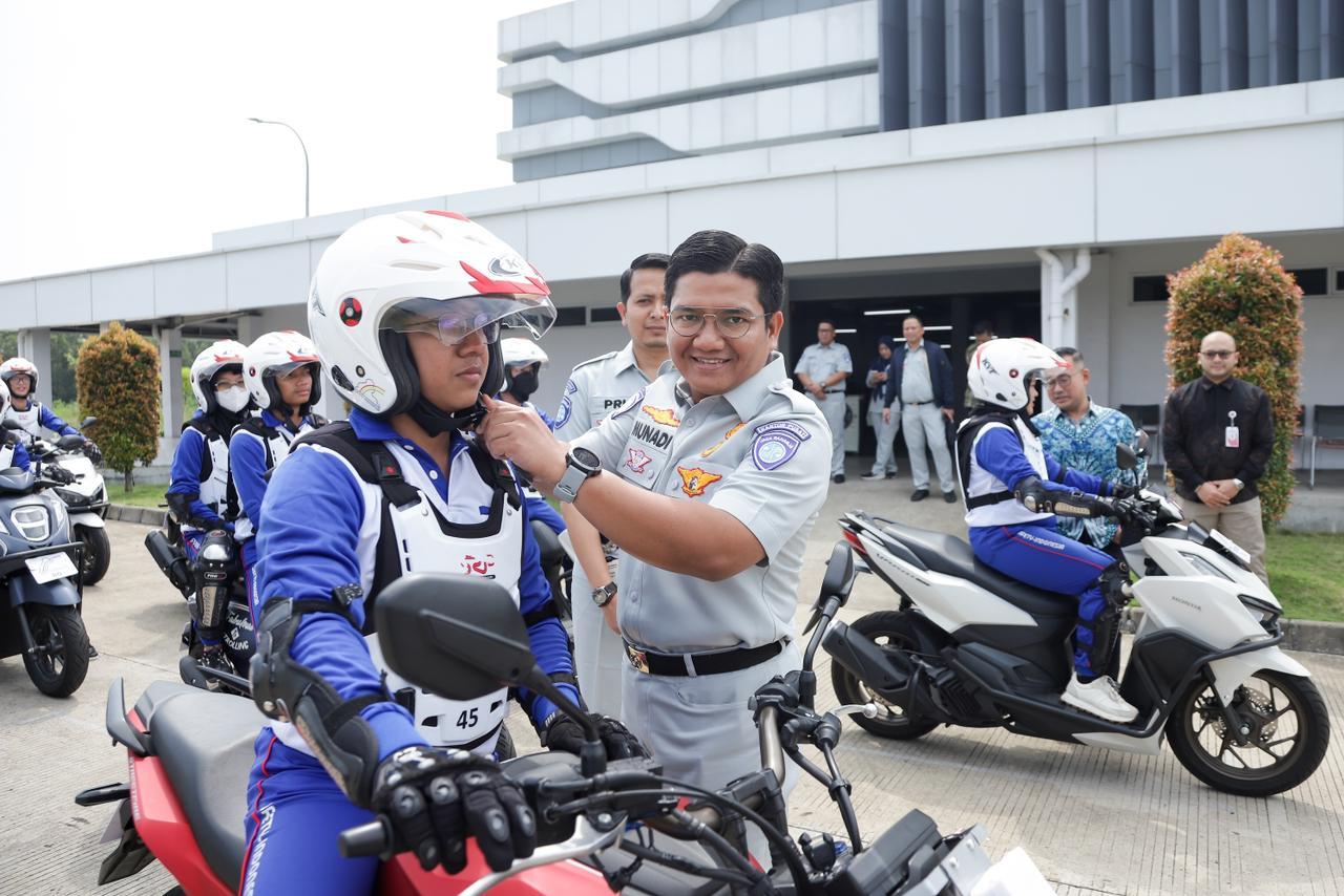 Direktur Hubungan kelembagaan Jasa Raharja, Munadi Herlambang saat memasangkan helm kepada salah seorang pengendara motor. FOTO: HUMAS JASA RAHARJA