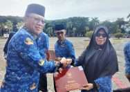 Staf Ahli Bupati Parmout Bidang Ekonomi Pembangunan dan Kesra, Mawardin (kiri) menyerahkan piagam satyalancana karya satya kepada kepada salah seorang ASN pada upacara tanggal 17 bulan berjalan di halaman Kantor Bupati Parmout, Rabu (17/1/2024). FOTO: DINAS KOMINFO PARMOUT.